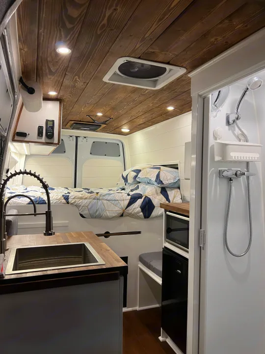 Cozy RV rental interior: bed, kitchen, & shower in a modern camper van with a beautiful wooden ceiling.. Mercedes-Benz Sprinter RV Motorhome Campervan 2022