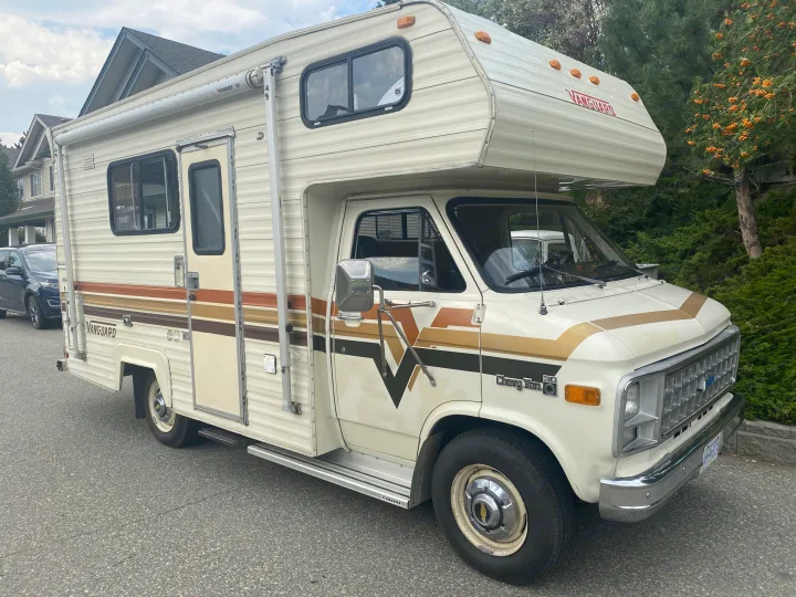This classic cream-colored Chevy Vanguard RV, adorned with retro stripes, is ready for an RV rental road trip adventure.. Vanguard Industries MV 1800 1981
