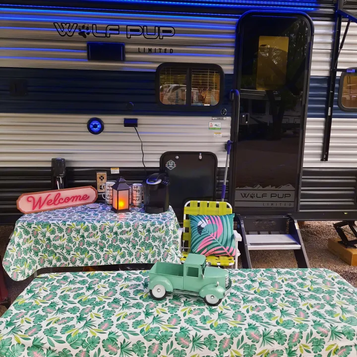 This Wolf Pup RV rental features a bright blue LED-lit side, a vibrant tropical outdoor setup with a Keurig coffee station and "Welcome" sign.. Forest River Cherokee Wolf Pup 2022