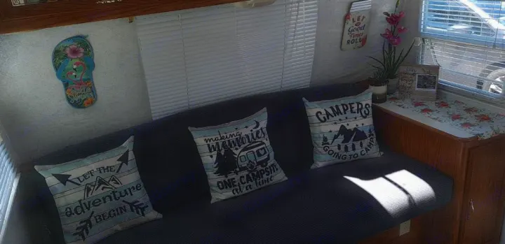 Cozy RV rental living space with camping-themed pillows, wall decor, and blinds, ready for adventure.. Shasta Flite 2000
