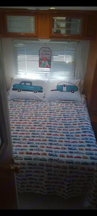 Cozy RV rental bedroom featuring vintage car bedding, a truck pillow, and a teardrop trailer pillow for a fun road trip vibe.. Shasta Flite 2000