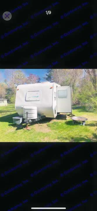 White RV rental parked outdoors with its door open and a fire pit nearby. Ideal for your next camping adventure.. Shasta Flite 2000
