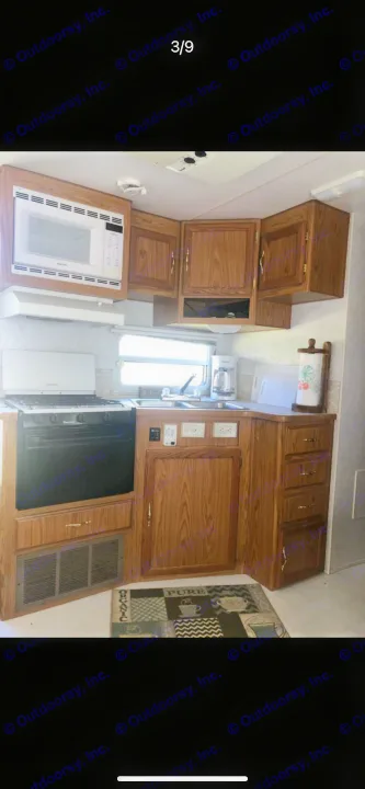 Well-equipped RV rental kitchen featuring a microwave, stove, sink, and wood cabinets. Ready for your trip!. Shasta Flite 2000