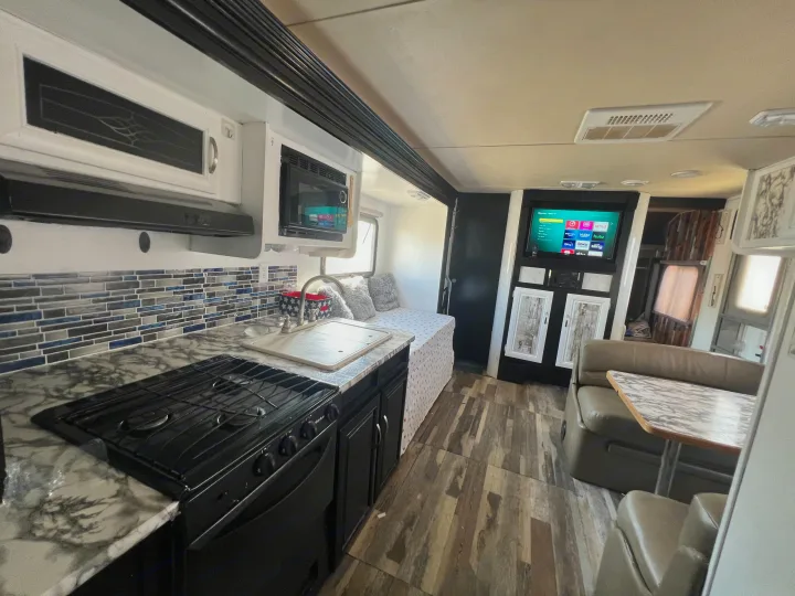 Spacious RV rental interior featuring a modern kitchen, comfortable living area with TV, and cozy bed.. Forest River Salem Cruise Lite 2014