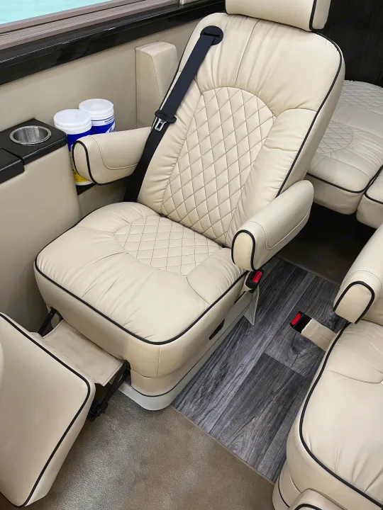 Luxury RV rental interior: Cream quilted captain's chair with seatbelt, side amenities, and wood-look flooring.. Midwest Automotive Designs Midwest Automotive Designs Class B 2021