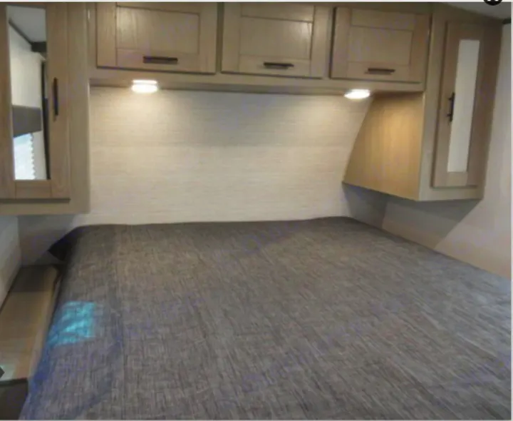 Inside an RV rental: a well-appointed bedroom with a bed, overhead cabinets, and task lighting for comfortable travel.. Cruiser RV Shadow Cruiser 2022