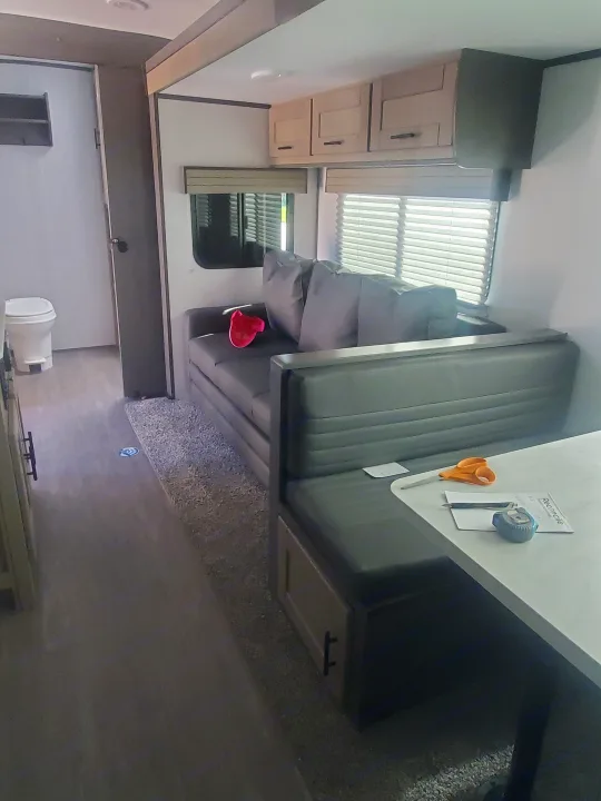 This rv rental features a modern interior with a grey sofa, dinette, overhead cabinets, and a visible bathroom. Ready for travel!. Cruiser RV Shadow Cruiser 2022