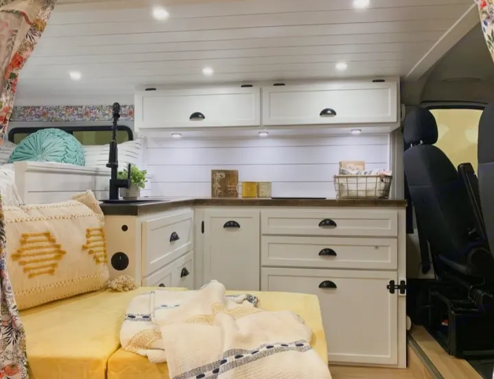 Cozy RV rental interior featuring a compact kitchenette with a sink, sleeping area, and white shiplap walls.. Dodge 1500 2016