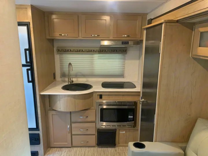 This RV rental kitchen features a sink, stovetop, microwave, fridge, and ample storage, ideal for compact travel.. R-Pod Hood River Edition 2020
