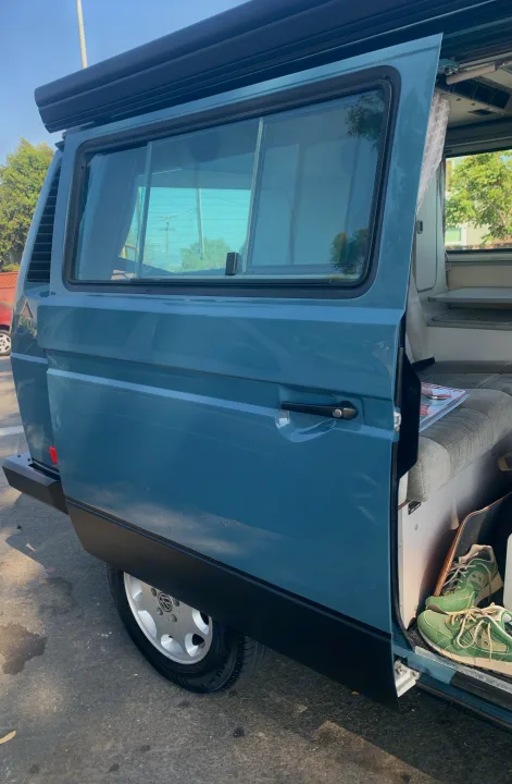 Blue camper van with side door open, revealing a cozy interior with seating, a table, and shoes. Perfect for an rv rental.. Volkswagen Westfalia 1990