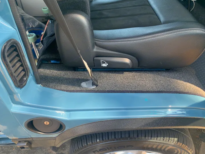 An RV rental interior features a black seat, frayed seatbelt, grey carpet, and light blue trim.. Volkswagen Westfalia 1990