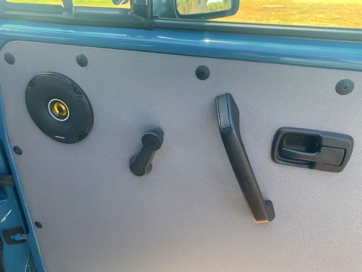 This RV rental's light blue door features a gray panel with Kicker speaker, manual window crank, armrest, and latch.. Volkswagen Westfalia 1990