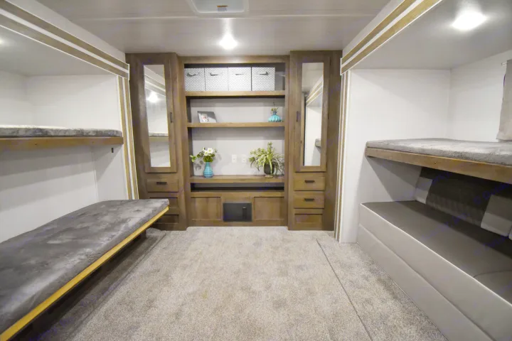 RV rental bunkhouse interior with multiple bunk beds, central wooden storage, & carpeted floor for comfortable stays.. Forest River Salem 2020