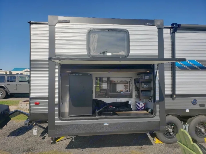 RV rental with side open, showing an outdoor kitchen featuring a fridge, TV, and sink, ideal for camping.. Forest River Salem 2020