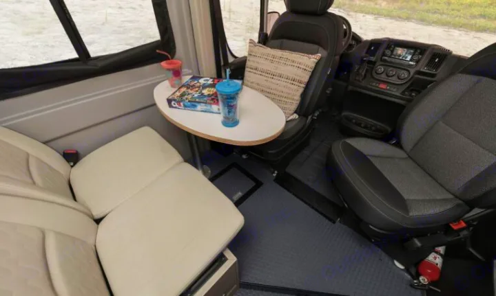 Inside an RV rental: flexible seating with swivel front chairs, a small table with a game, and a bench.. Winnebago Solis 2022