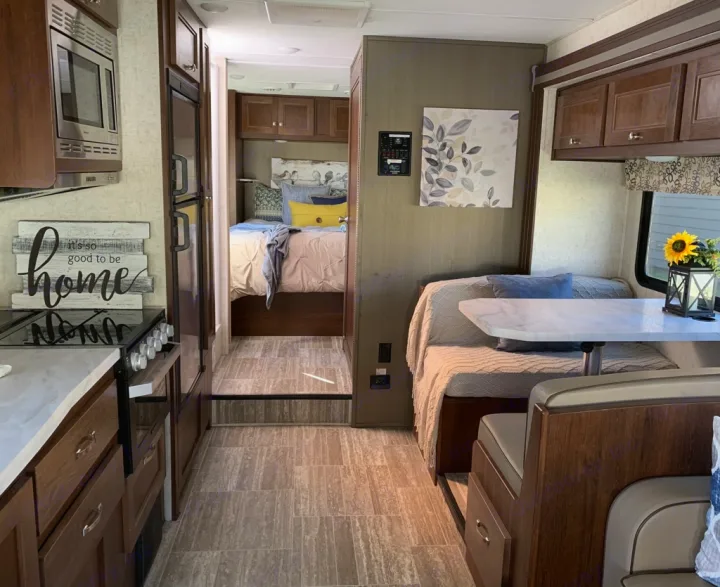 Inside this charming RV rental: a modern kitchen, inviting dinette with sunflower decor, and comfy bedroom beyond.. Forester LE 2020