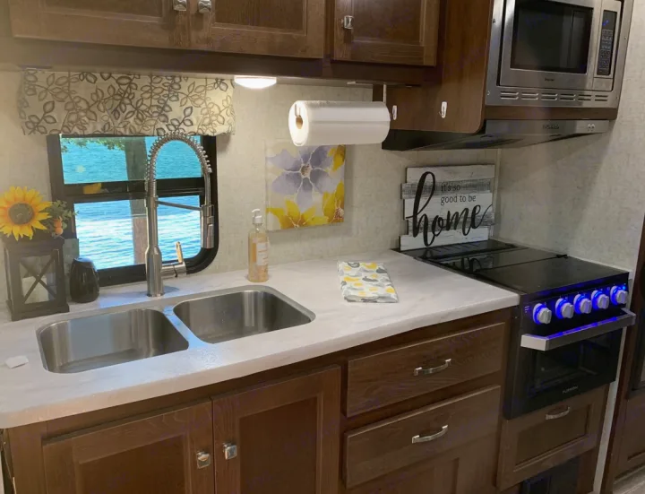 Inviting RV rental kitchen with dual sink, stove, microwave, and lake view. A cozy interior for your travel adventures!. Forester LE 2020