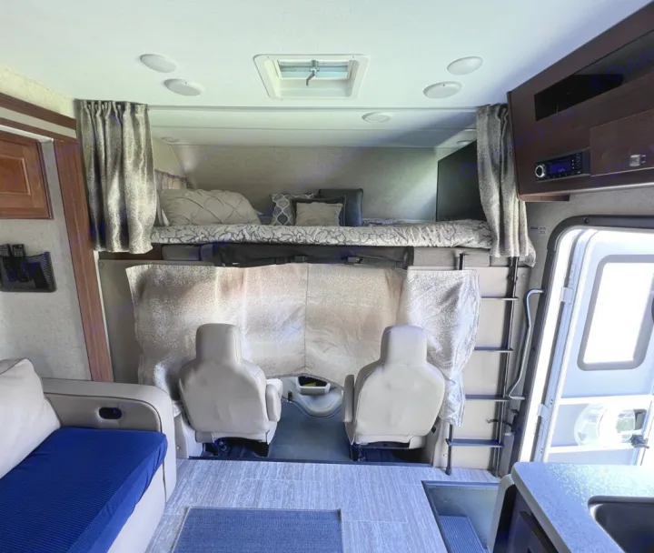This cozy rv rental interior features a spacious bunk bed, swivel seats, and a compact kitchen, ideal for comfortable travel.. Forester LE 2020