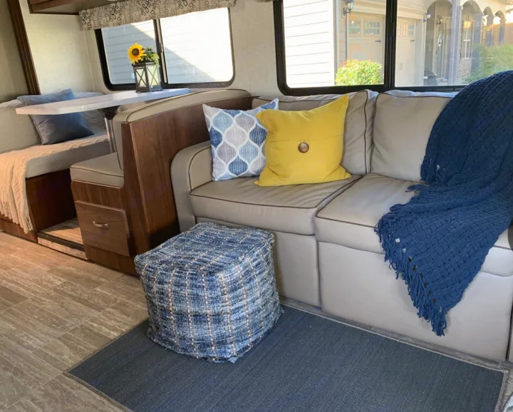 Cozy RV rental interior featuring a comfortable dinette, sofa with pillows and a blue throw, plus a patterned pouf.. Forester LE 2020