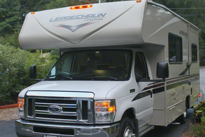 Detailed front view of a white & tan Coachmen Leprechaun Class C RV with lights on, perfect for your next rv rental.. Forest River Coachmen Leprechaun 2022