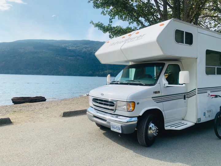 Adventurer RV rental parked by a tranquil lake with mountains in British Columbia, ideal for exploration.. Slumber Queen Adventurer 2001