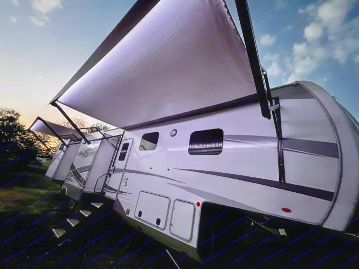 Enjoy an RV rental adventure! This illuminated travel trailer at dusk features bright awnings under a crescent moon.. Highland Ridge RV Open Range 2021