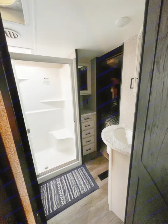 Explore this modern RV rental bathroom: a spacious shower, sleek vanity with sink, handy drawers, and bedroom access.. Highland Ridge RV Open Range 2021