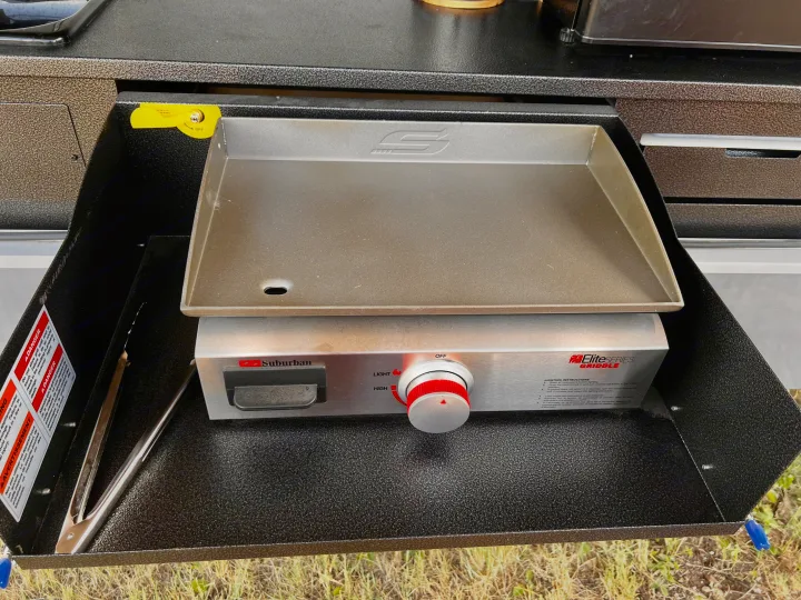 This RV rental's outdoor kitchen features a pull-out Suburban griddle for easy camp cooking and outdoor meals.. Highland Ridge RV Open Range 2021