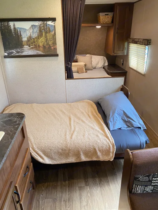 Compact RV rental interior featuring a lower bed, an upper bunk with privacy curtain, and overhead storage, perfect for travel.. Jayco Jay Flight SLX 2016