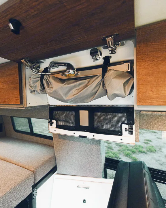 Compact RV rental interior featuring a fold-out sink/shower and clever overhead storage with mesh pockets.. StoryTeller Overland Classic Mode 4X4 2022