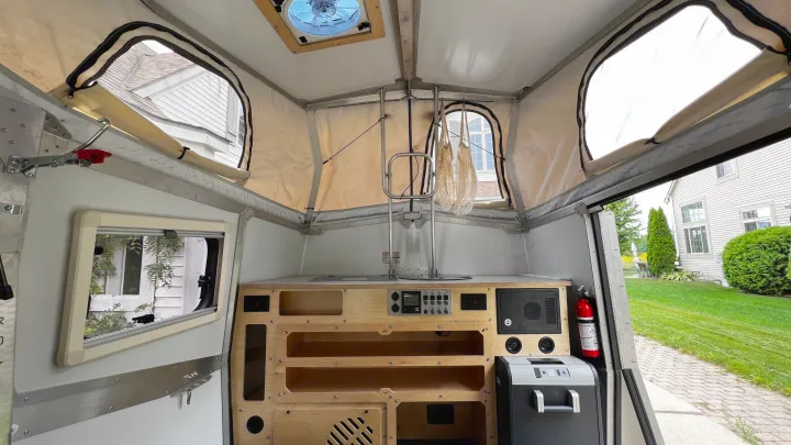 Compact pop-up camper interior: kitchen, controls, storage, and a fan, ready for your next rv rental adventure.. TAXA Cricket Overland Edition 2020