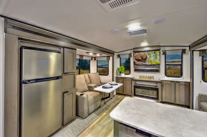 Inside this modern RV rental: a cozy living area with recliners, entertainment, kitchen, and bright windows.. Cruiser RV MPG Ultra Lite 2022