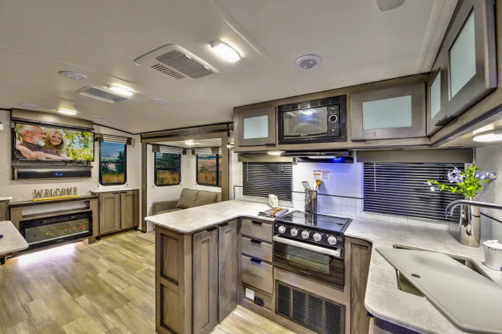 Spacious RV rental interior featuring a modern kitchen, living room with TV, and fireplace.. Cruiser RV MPG Ultra Lite 2022