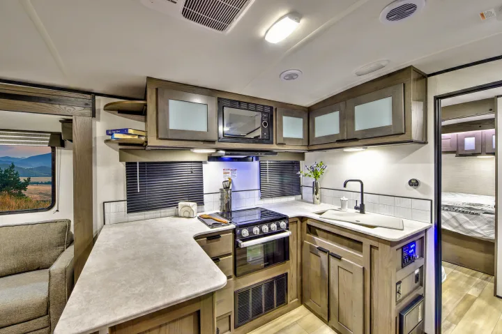 Modern RV rental interior featuring a bright kitchen, cozy sofa, and bedroom entrance. Ready for adventure!. Cruiser RV MPG Ultra Lite 2022