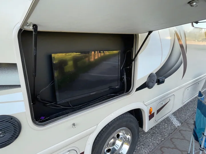 An RV rental with an open side compartment revealing an outdoor TV for camping and entertainment.. Thor Quantum 2017