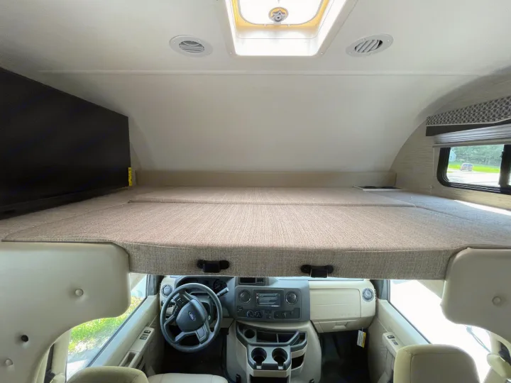 Inside an RV rental, showing the cab-over bunk with a TV above the. Thor Four Winds 2022