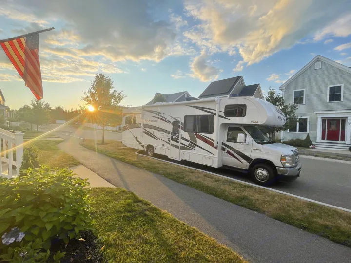 White Four Winds RV rental parked on a residential street at sunset. Thor Four Winds 2022