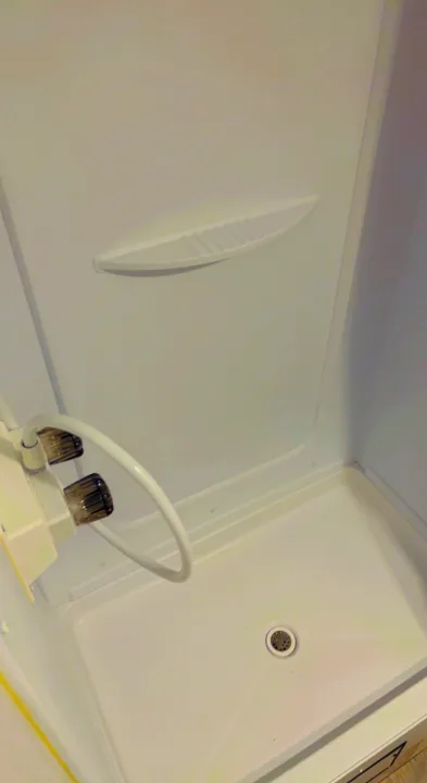 A clean, white, compact shower stall with a flexible hose and drain, commonly found in an RV rental.. Keystone RV Springdale 2022