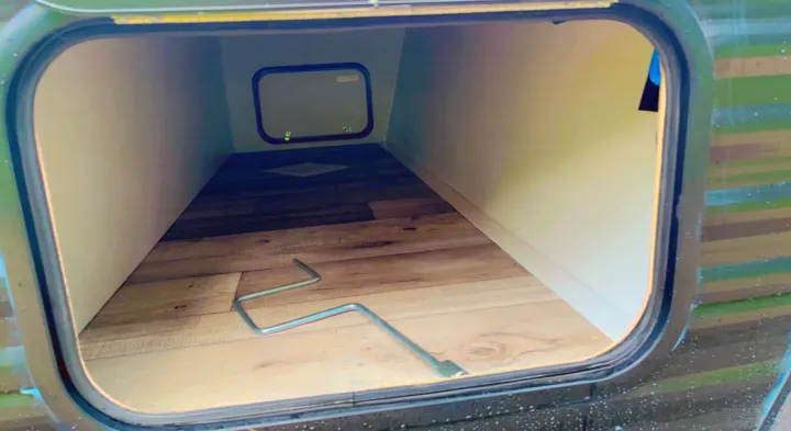 RV rental: Wood-paneled bunk interior with a small window and handle, viewed through the entry opening.. Keystone RV Springdale 2022