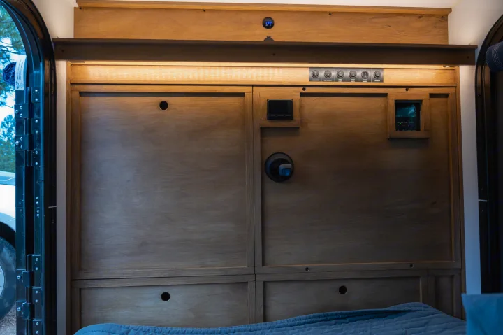 RV rental interior: wooden panels, power controls, thermostat, and bed, providing comfort and functionality.. White River X Camper Trail Explorer 2021