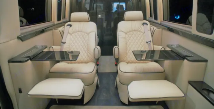 Step inside a premium RV rental: spacious interior with two plush captain's chairs, footrests, and side tables.. Ultimate Toys Ultimate Coach 2022