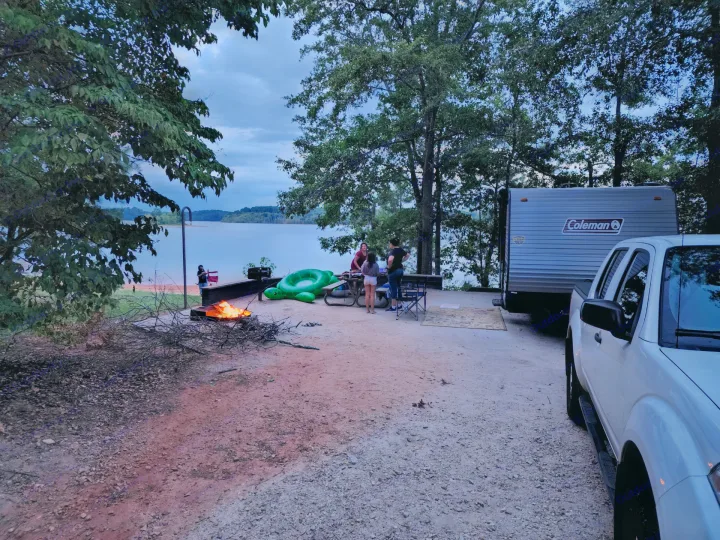 Lakeside camping with an RV rental, featuring a warm campfire and family gathering at dusk.. Dutchmen Coleman Lantern LT 2022