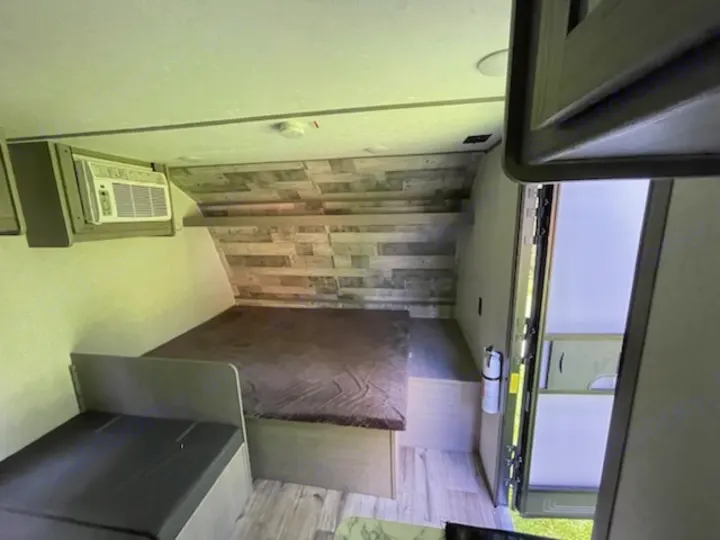 Compact travel trailer RV rental interior: bed, AC unit, seating. Ready for adventure.. Dutchmen Coleman Lantern LT 2022