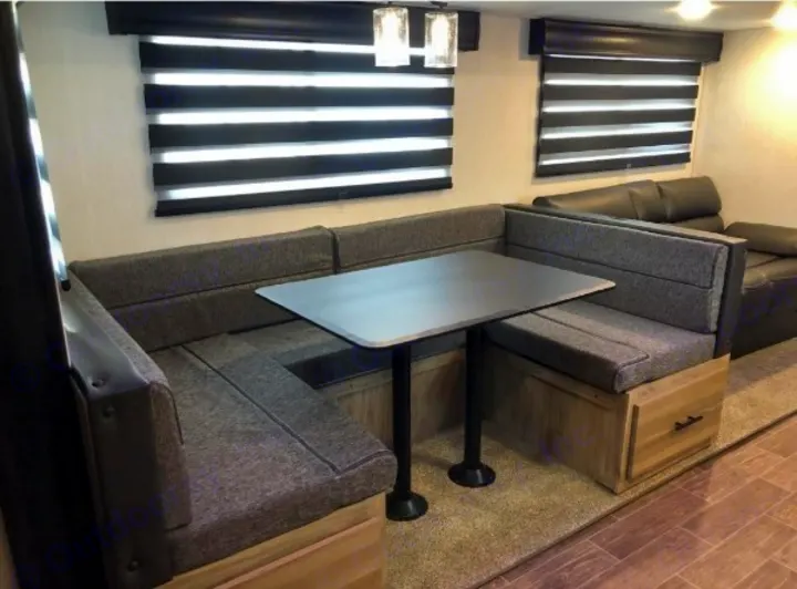 Inside an RV rental: a comfortable U-shaped dinette with grey fabric seating, a table, and storage drawers. Ideal for meals.. Forest River Cherokee Alpha Wolf 2022