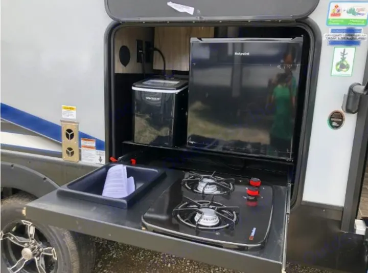 RV rental outdoor kitchen featuring a mini-fridge, ice maker, two-burner stove, and sink for convenient camping.. Forest River Cherokee Alpha Wolf 2022