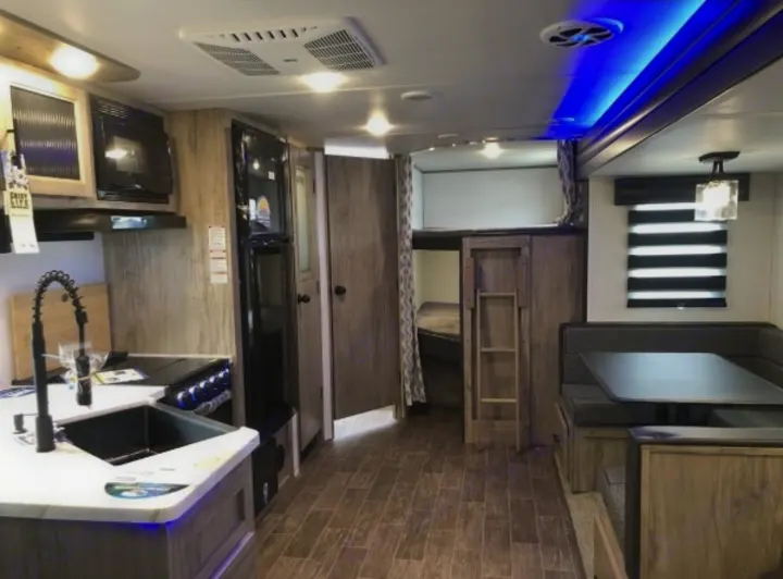Interior view of an RV rental: features a well-appointed kitchen, comfortable dining booth, and built-in bunk beds.. Forest River Cherokee Alpha Wolf 2022