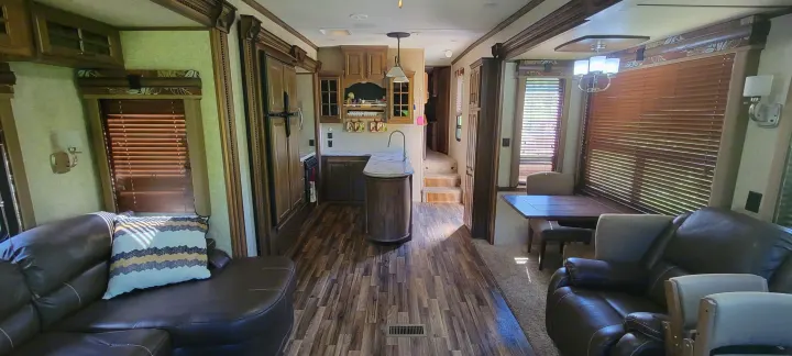Spacious RV rental interior featuring a full kitchen, dining area, and comfortable living room seating with an L-shaped sofa.. Keystone RV Alpine 2015