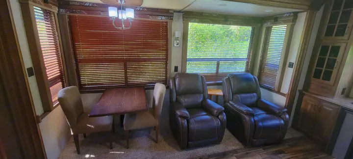 Inviting RV rental interior featuring a dining table with chairs and two plush recliners.. Keystone RV Alpine 2015