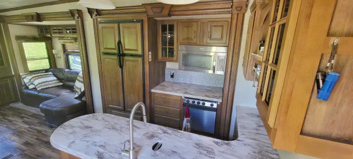 Explore this RV rental's full kitchen with sink, microwave, stove, and fridge, plus a cozy living area with sofa.. Keystone RV Alpine 2015