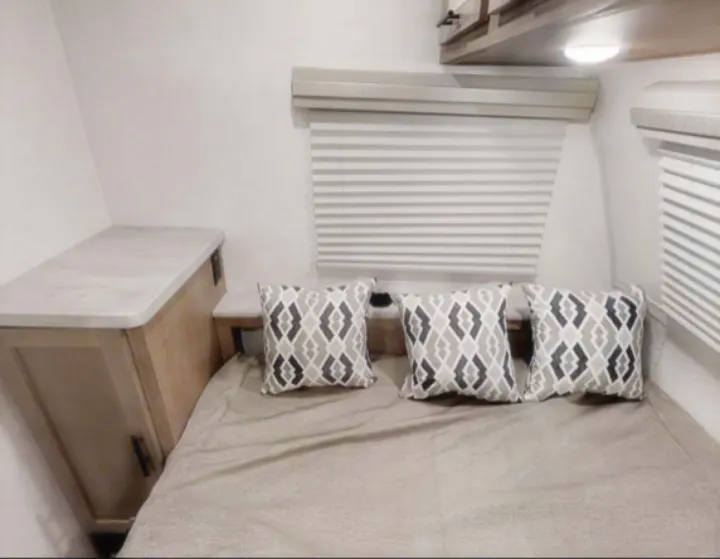 Cozy RV bedroom for your next rv rental adventure, featuring a bed, patterned pillows, and blinds for comfort.. Forest River no boundaries 2020